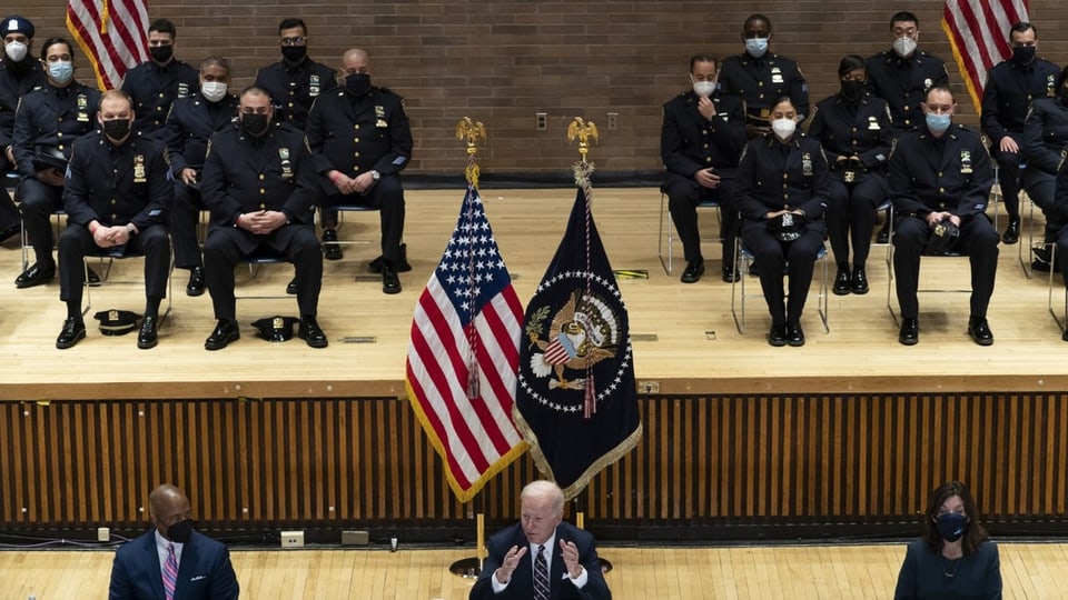 Polizistinnen und Polizisten im Hintergrund, Biden und Adams im Vordergrund.