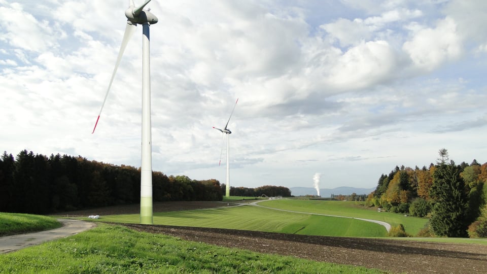 Montage einer Luftaufnahme mit vier Windturbinen inmitten der Landschaft.