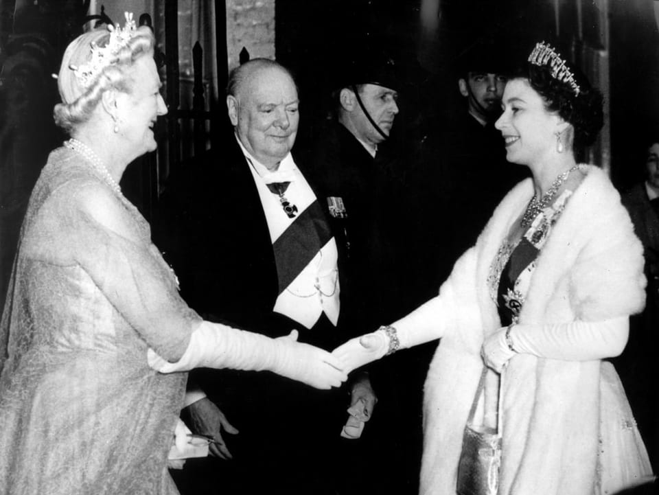 Die Queen begrüsst eine Frau mit einem Händedruck, daneben steht ein Mann im Anzug.