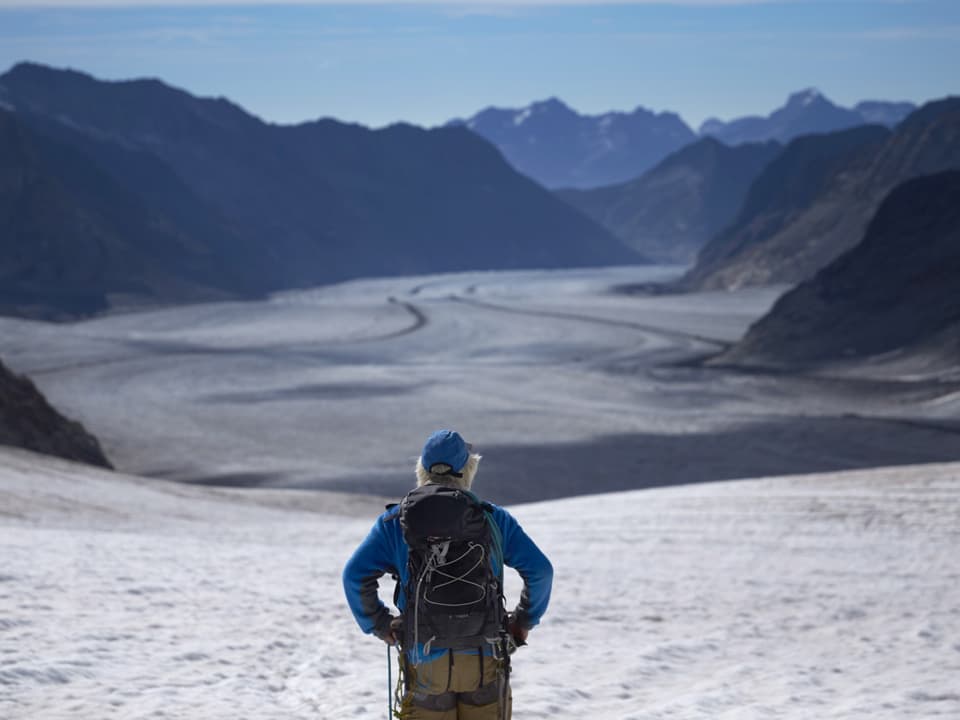 Ein Bergsteiter steht vor dem Gletscher, der in der Ferne entschwindet.