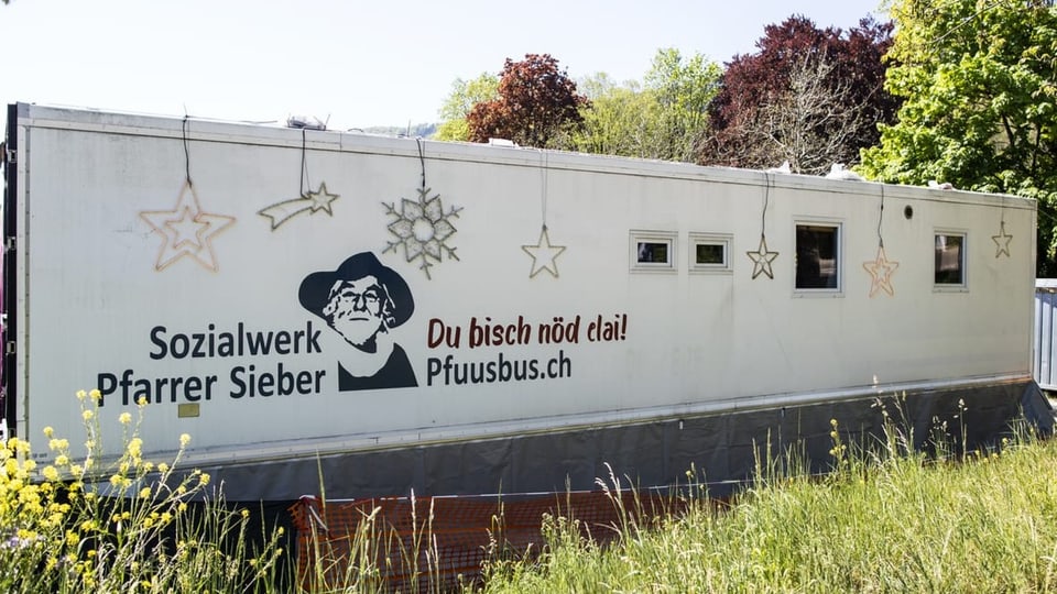 Bus mit der Aufschrift «Sozialwerk Pfarrer Sieber» steht auf einer Wiese neben Bäumen