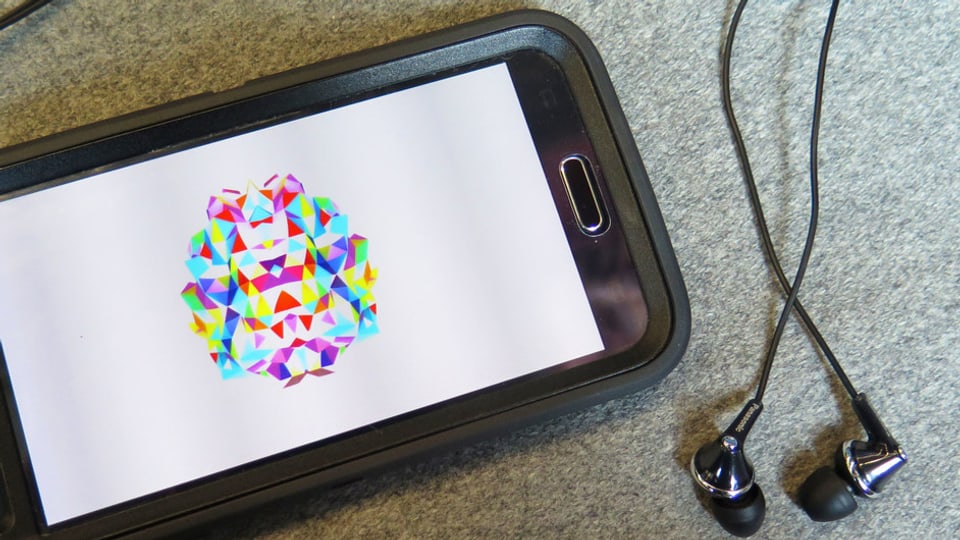 Der Screen eines Smartphones mit einem farbigen Bild. Daneben liegen Kopfhörer. 