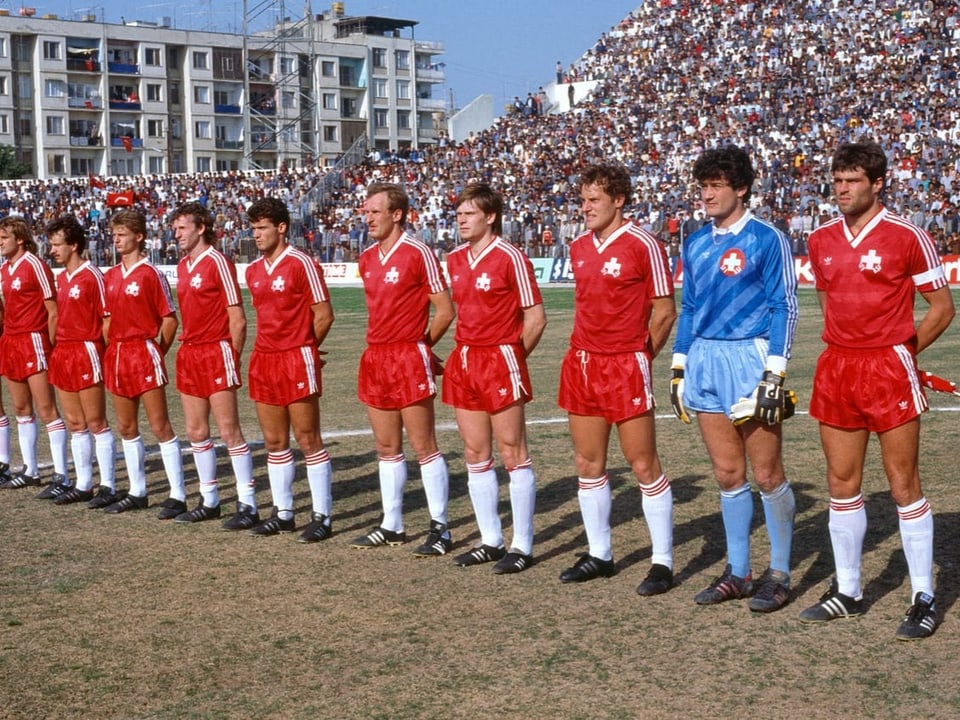 Fussballspieler stehen in einem Stadion in einer Reihe für die Nationalhymne.