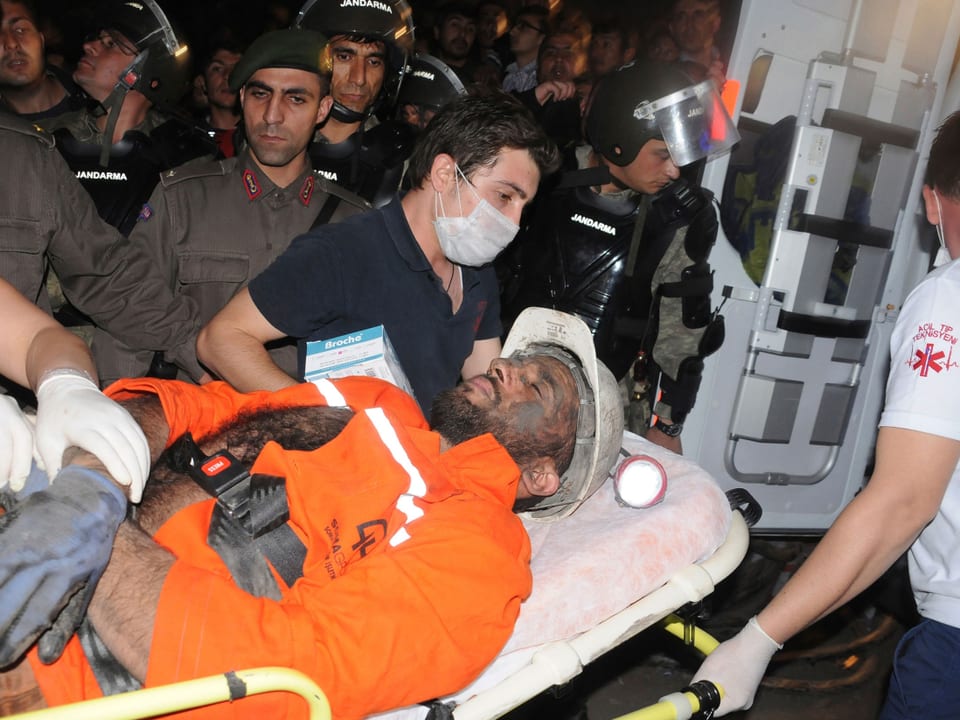 Ein Kumpel wird auf einer Bahre in den Krankenwagen geladen.
