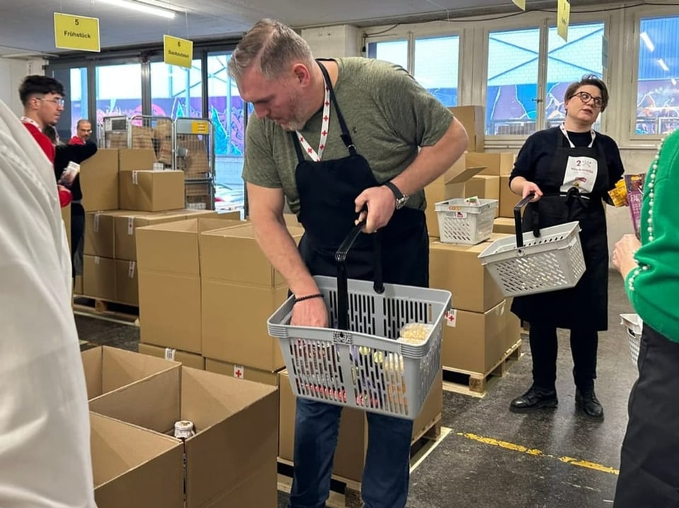 Christian Stucki füllt einen Einkaufskorb voller Spenden aus einem Karton