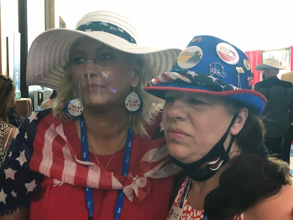 Zwei Frauen tragen Hüte, Anstecker und Schals