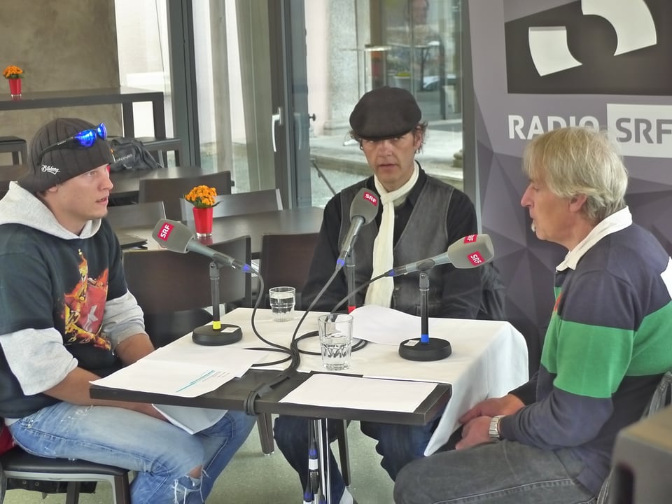 Zu sehen sind die drei Gastgeber von Radio Narrenfreiheit Marco, Bernd und Daniele. Daneben leuchtet eine rote Radiolampe.