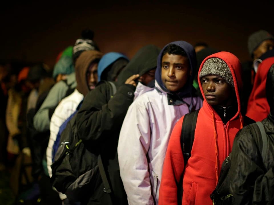 Migranten in einer Schlange auf der dunklen Strasse.