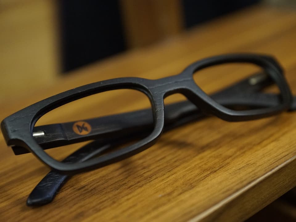 Eine Holzbrille auf einem Holztisch.