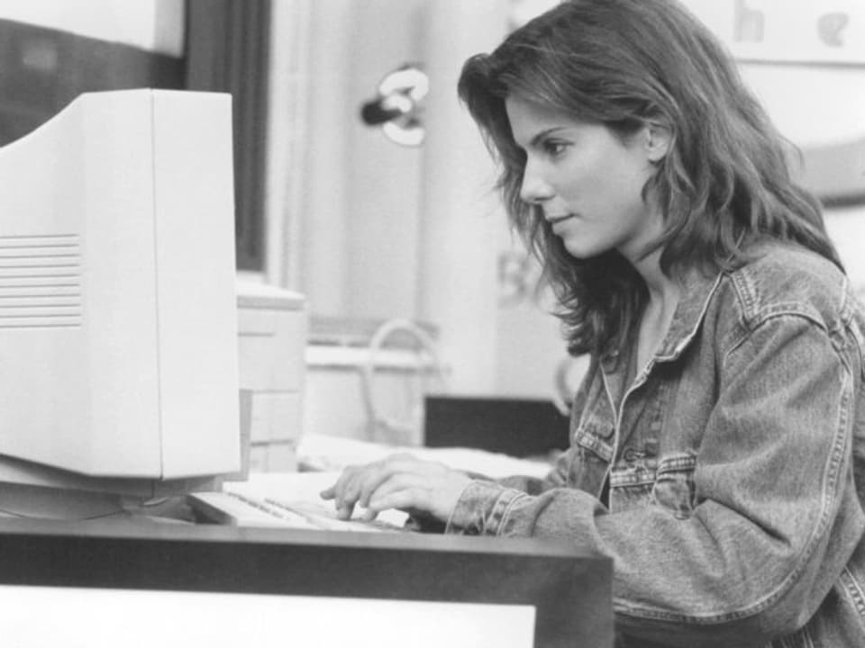 Sandra Bullock sitzt an einem Arbeitsplatz, tippt auf einem Keyboard.