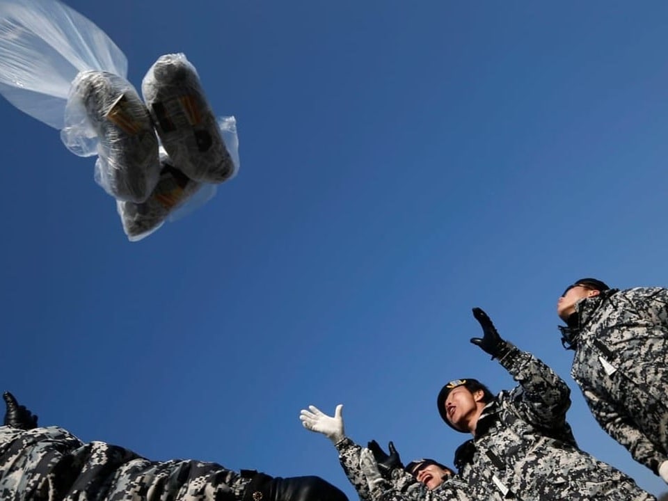 Soldiers throw packages into the sky.