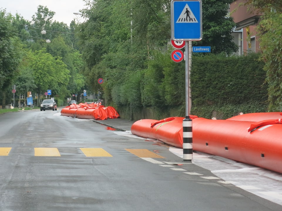 Rote Schläuche neben einer Strasse.