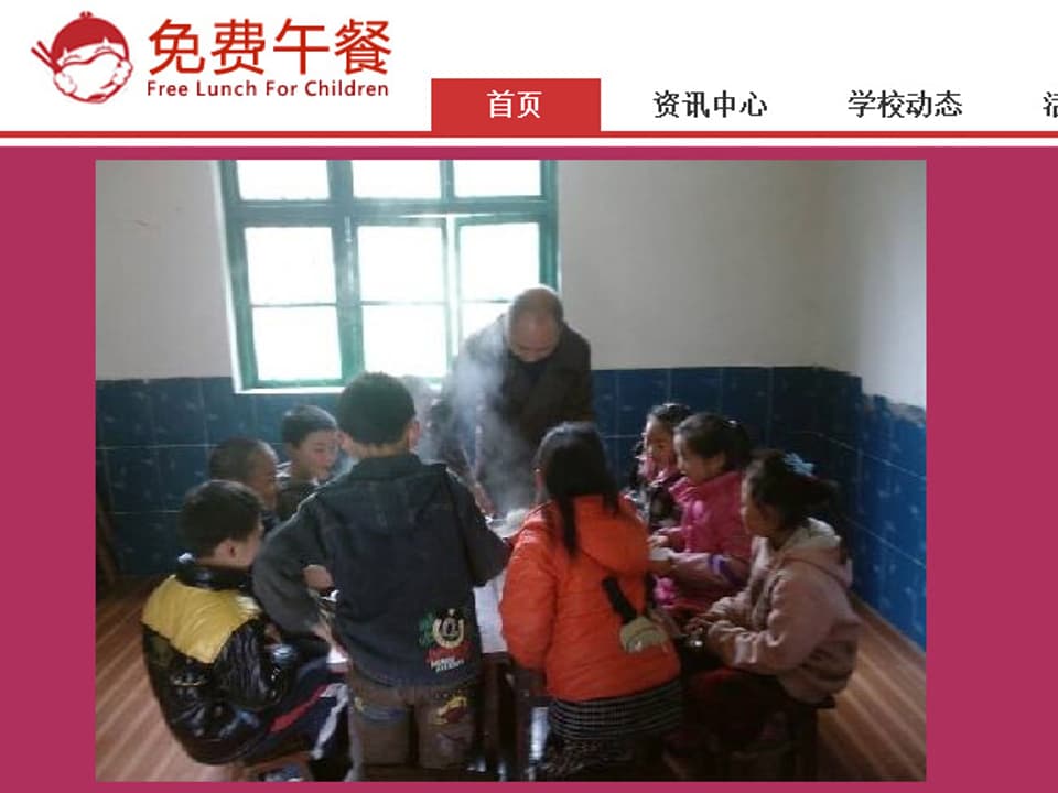 Eine Gruppe von Kindern sitzt um einen Tisch, ein Erwachsener schöpft essen aus.