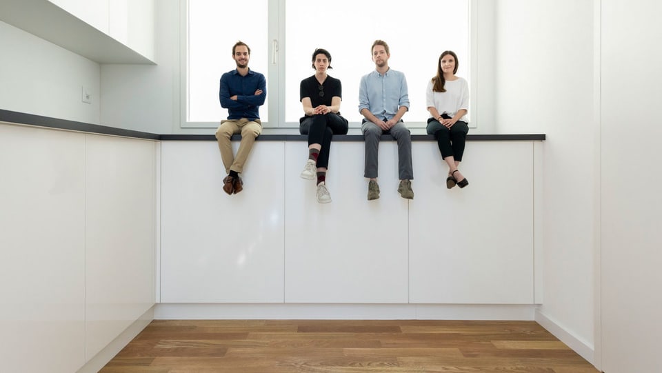 Vier Menschen sitzen auf einer hohen Diele.