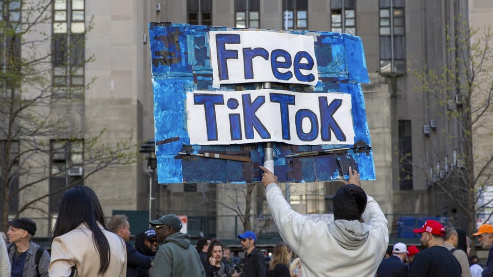 Person hält ein Schild mit der Aufschrift 'Free TikTok' bei einer öffentlichen Versammlung
