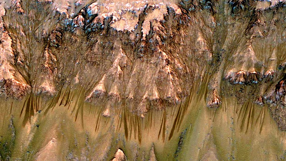 Bergflanke auf dem Mars. Abfallend daran sind Rillen zu sehen, die auf die zumindest sporadische Gegenwart von flüssigem Wasser hindeuten.