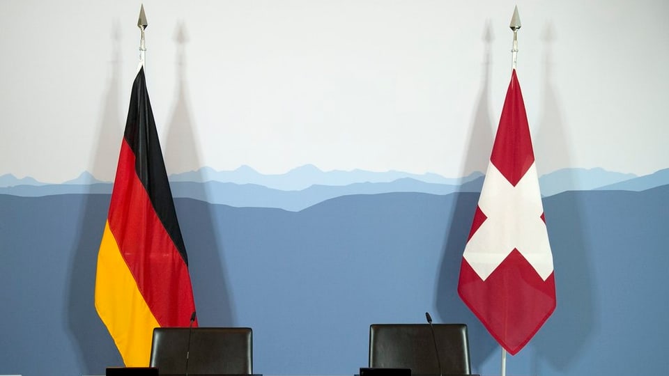Leere Stühle vor einer Schweizer und einer Deutschen Flagge.
