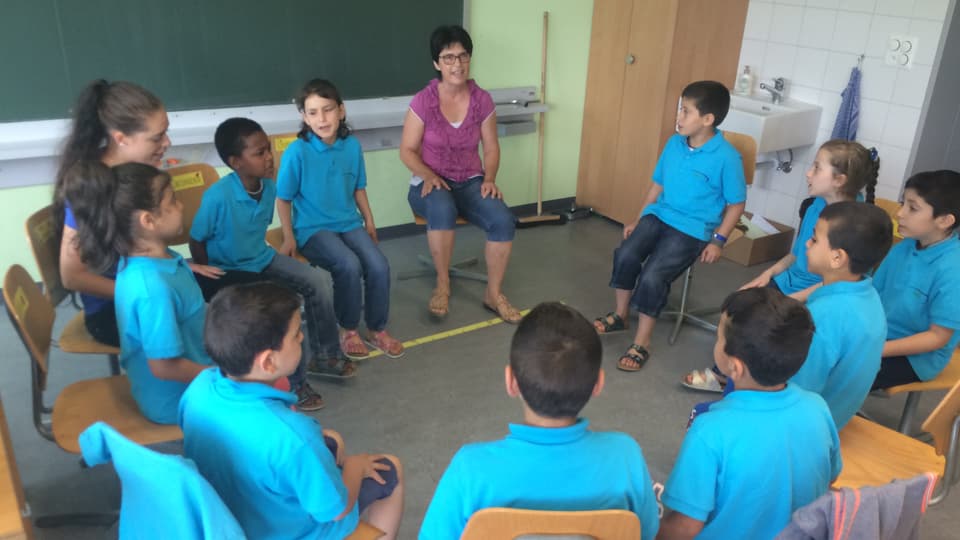 Syrische Kinder sitzen in einem Kreis und lernen Deutsch.