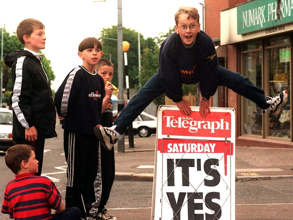 Ein Junge springt über einen Plakatständer auf dem zu Lesen ist: «It's Yes».