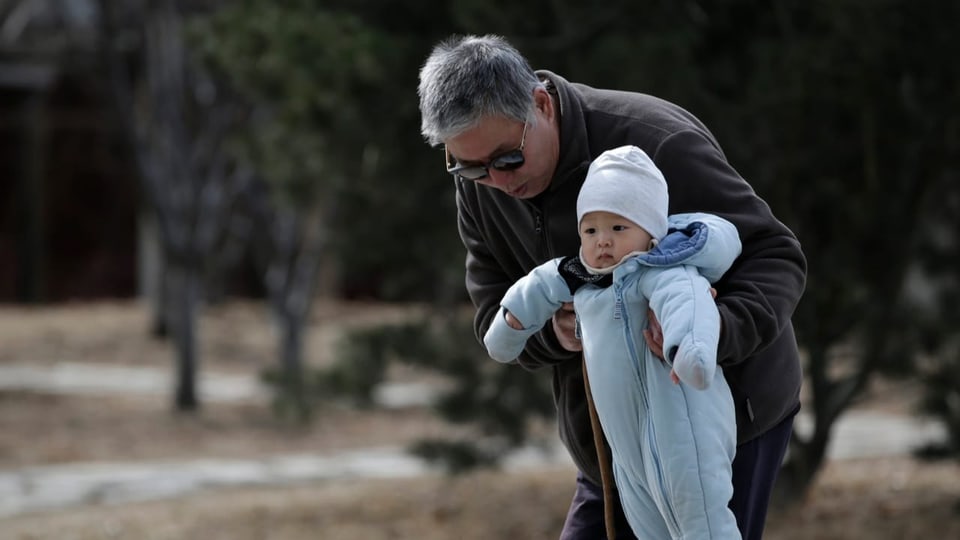 Ein Grossvater hält sein Enkelkind in der Hand
