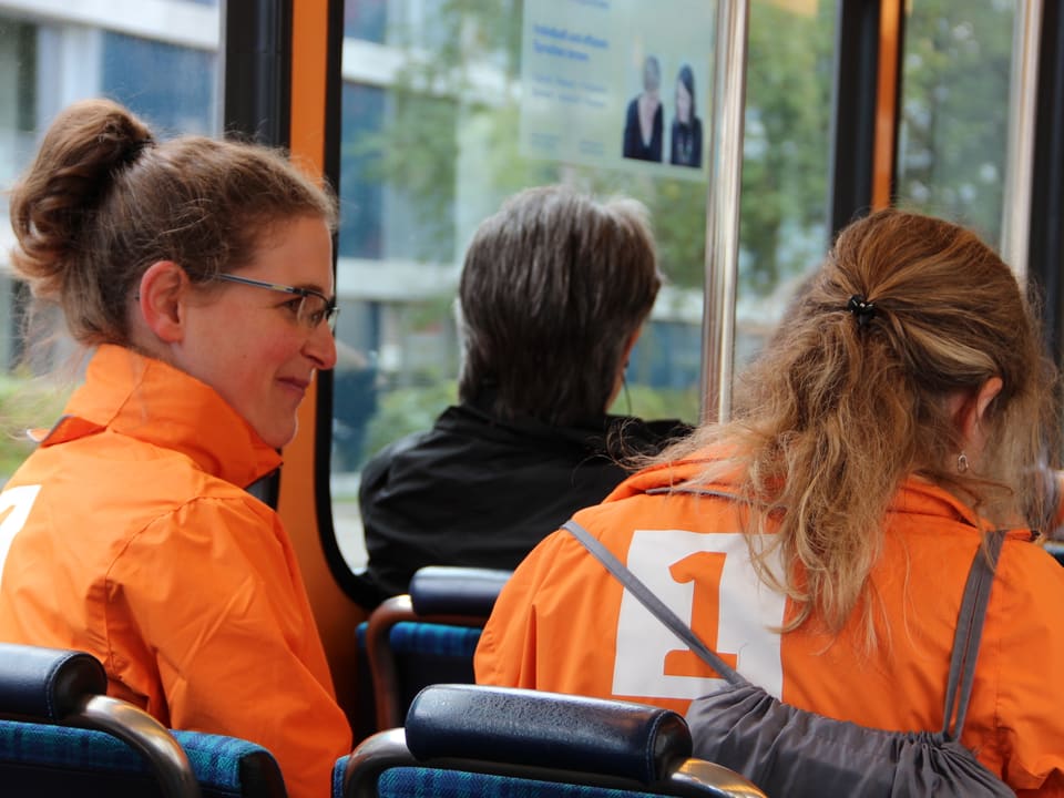 Katia Ambrosini in oranger Radio SRF 1-Jacke sitzt im Tram, das sie zum Landesmuseum fährt.