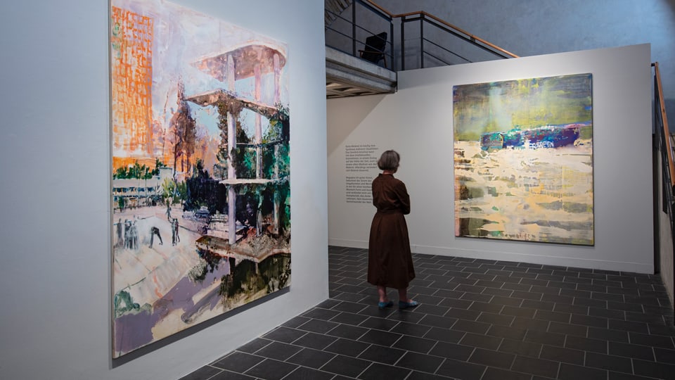 A woman stands in front of a painting and looks at it.