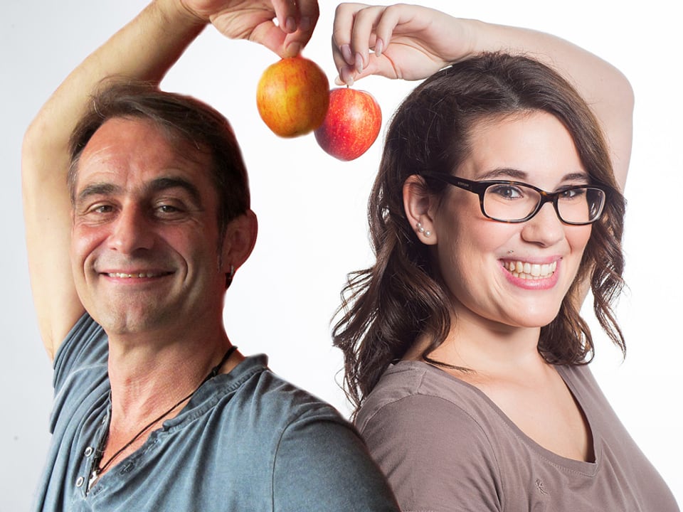 Stefanie König und Thomy Scherrer stehen Rücken an Rücken, beide halten einen Apfel in der Hand, die sie über den Kopf halten.
