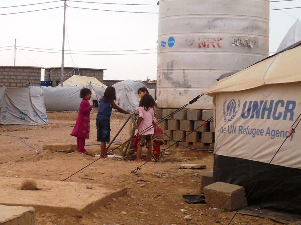 Kinder an einem Wasserspeicher im einem Zeltlager nahe Erbil.