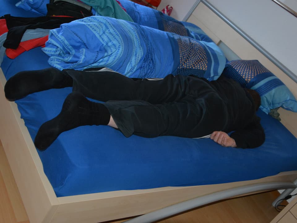 Michael liegt auf dem Bauch auf seinem Bett.