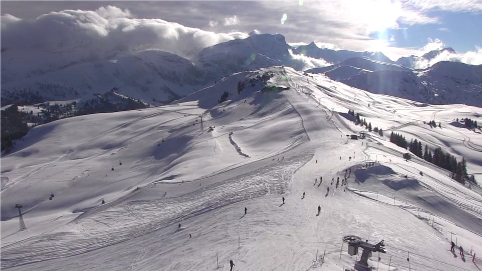 Skigebiet, dahinter die Berner Alpen, über denen die typische Wolkenmauer bei Föhn erkennbar ist.  Im Skigebiet dagegen scheint die Sonne.