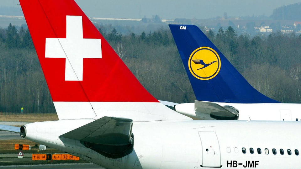 Zwei Heckflossen von Flugzeugen. Eine Maschine der Swiss Airline im Vordergrund, hinten ein Flugzeug der Lufthansa.