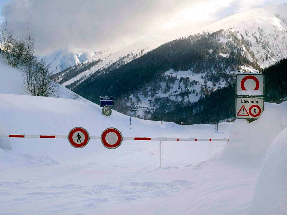 Viel Schnee im Gebiet rund um Ulrichen, die Strasse ist mit einer Barriere gesperrt, die Warnschilder zeigen Lawinengefahr.