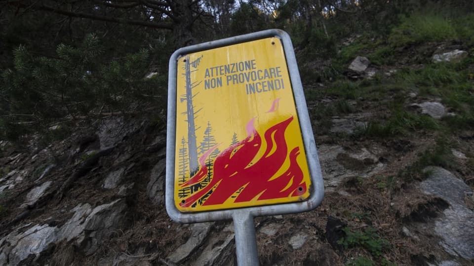 Gelbes Schild mit roten Flammen und einer schwarzen Schrift «Attenzione non provocare Incendi» steht vor einem Wald