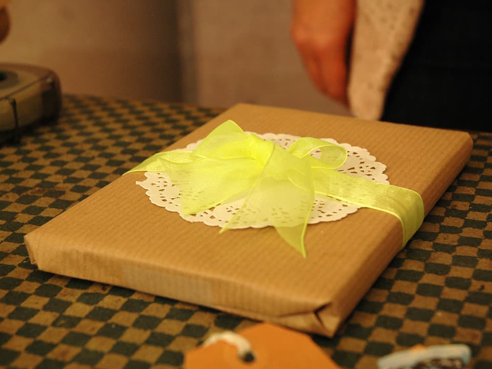 Geschenk in Packpapier mit einem weissen Tortenboden und einem gelben «Bändeli».
