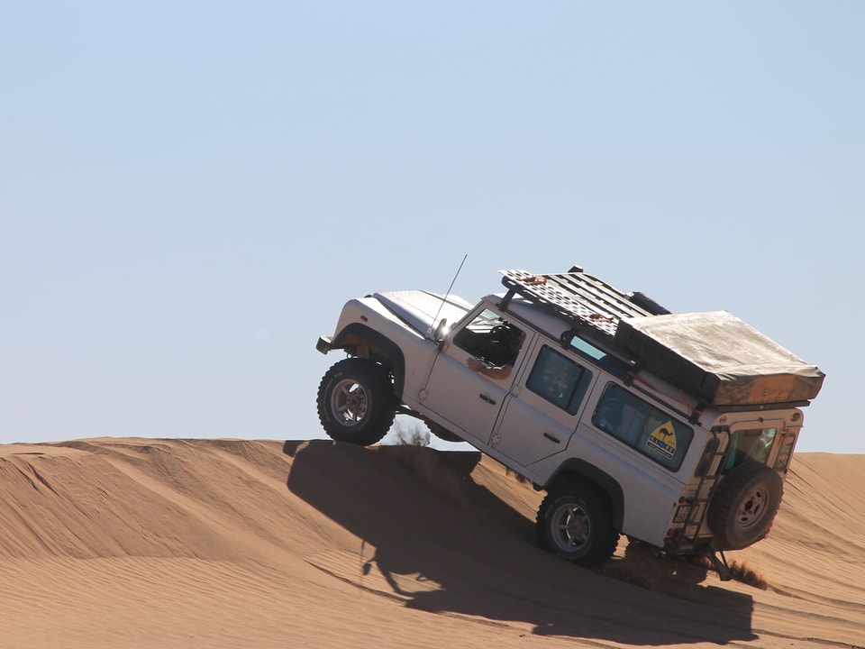 Jeep, der in der Wüste über eine Bühne sprignt