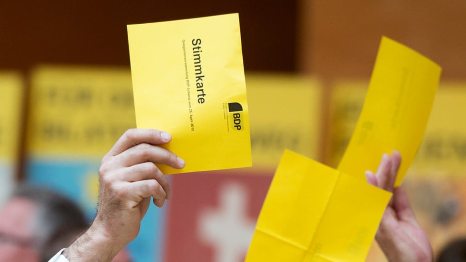 Ein Mann hält an der Versammlung der BDP eine gelbe Wahlkarte in die Höhe.