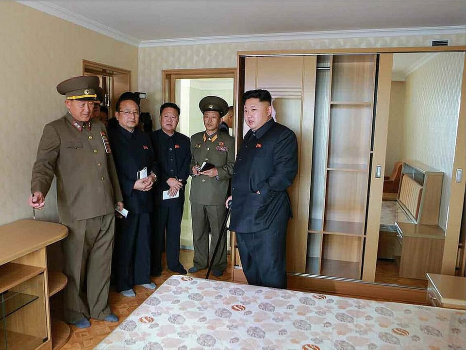 Kim mit anderen Männern in einem Schlafzimmer.