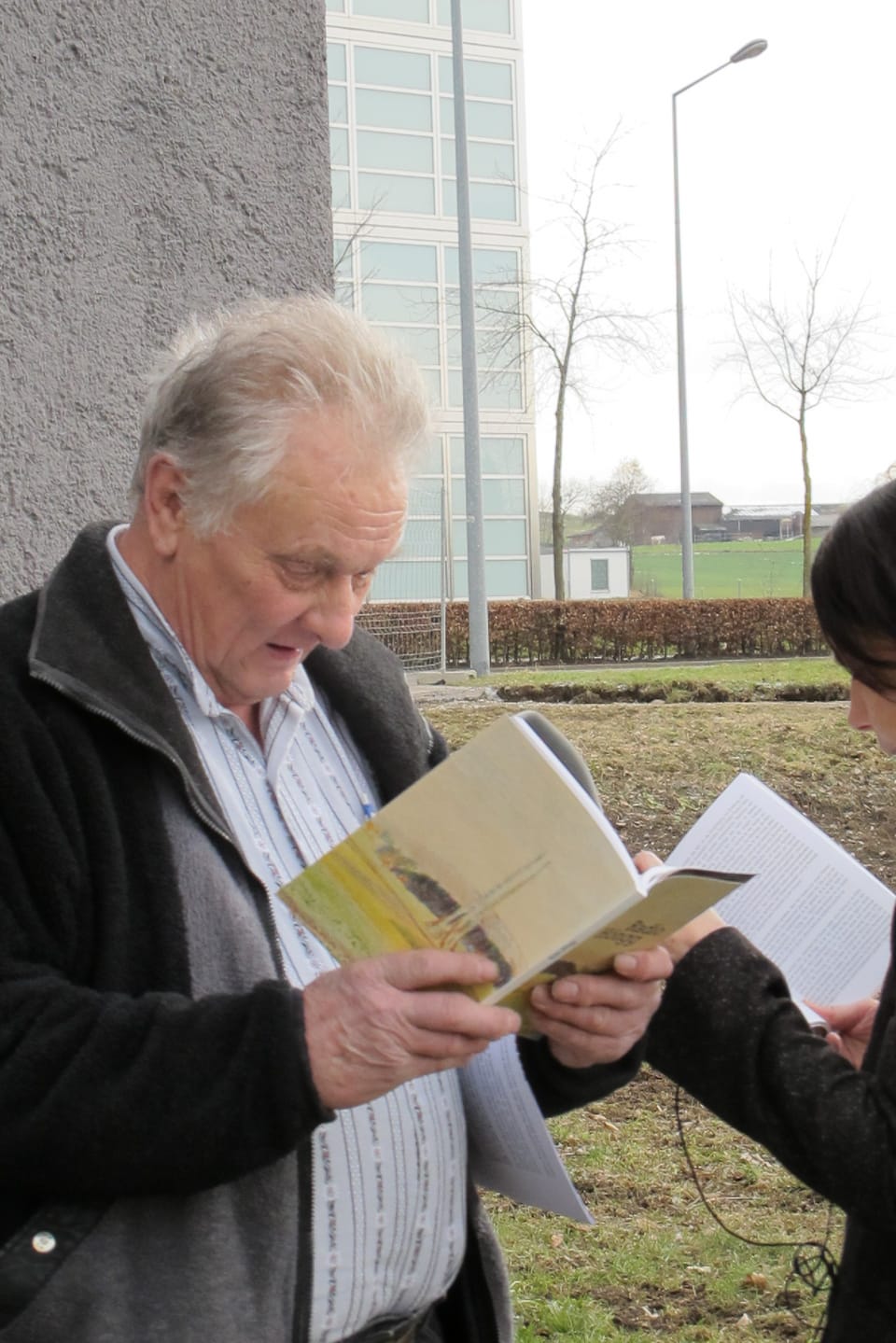 Ein älterer Mann liest aus einem Buch.