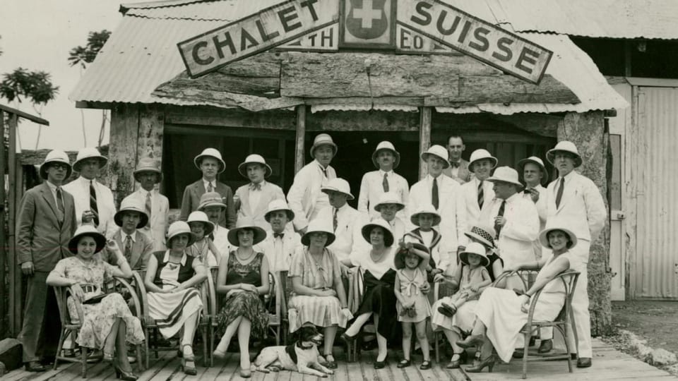 Schwarzweissbild: Gruppe von Menshcen vor einem Haus mit der Aufschrift «Chalet Suisse»