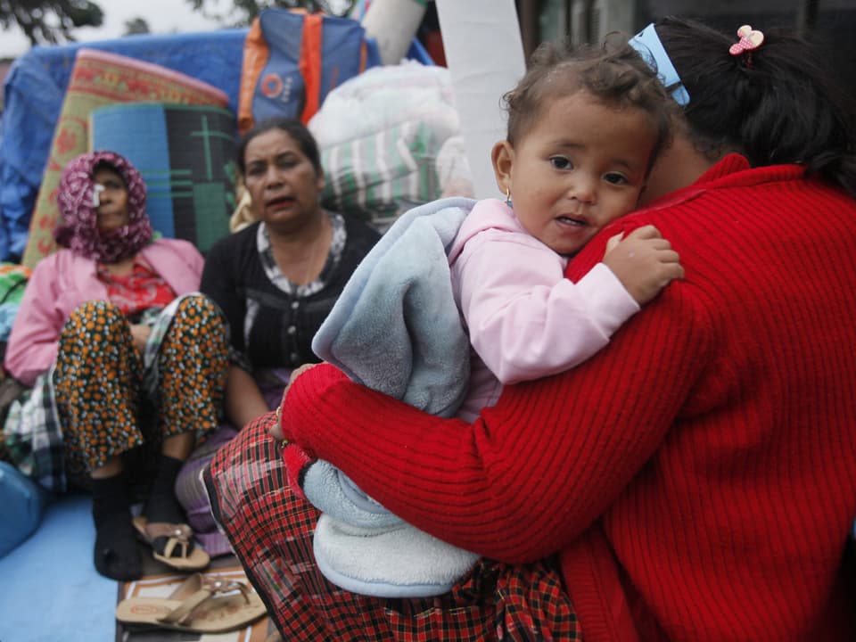 Ein Baby in den Armen ihrer Mutter. Sie warten, bis sie in Sicherheit gebracht werden.