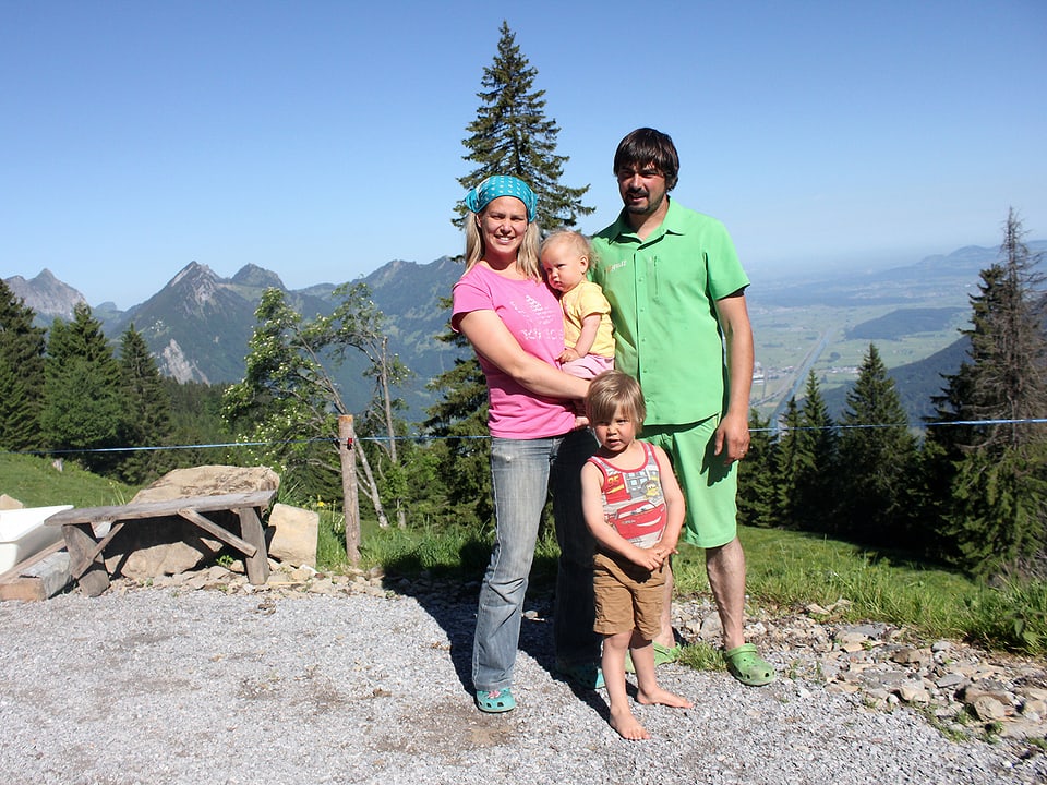 Rahel und Christian Beglinger mit zwei Kindern, dahinter schöne Berglandschaft.