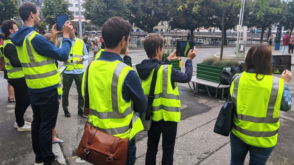 Menschen mit Leuchtwesten halten Tablet hoch