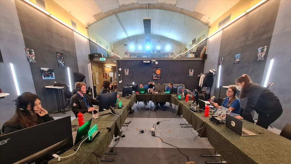 Leute an Laptops und Computern in einer Bunkerhalle.