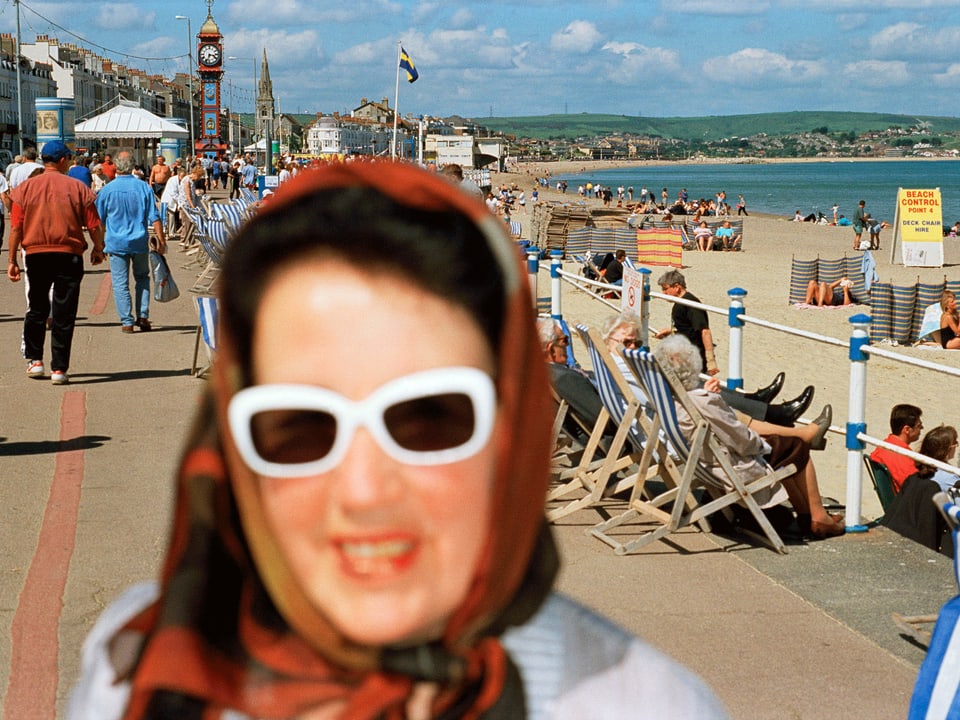 Frau mit Kopftuch und Brille, im Hintergrund Strandpromenade.