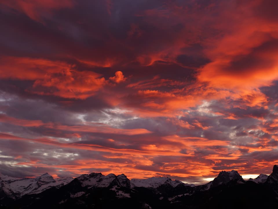 Bewölkter Himmel in rot, unten Blick auf die Alpen