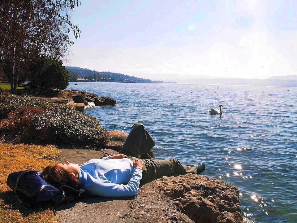 Ein Frau, am Ufer des Zürichsees, lässt sich von der Märzsonne verwöhnen.
