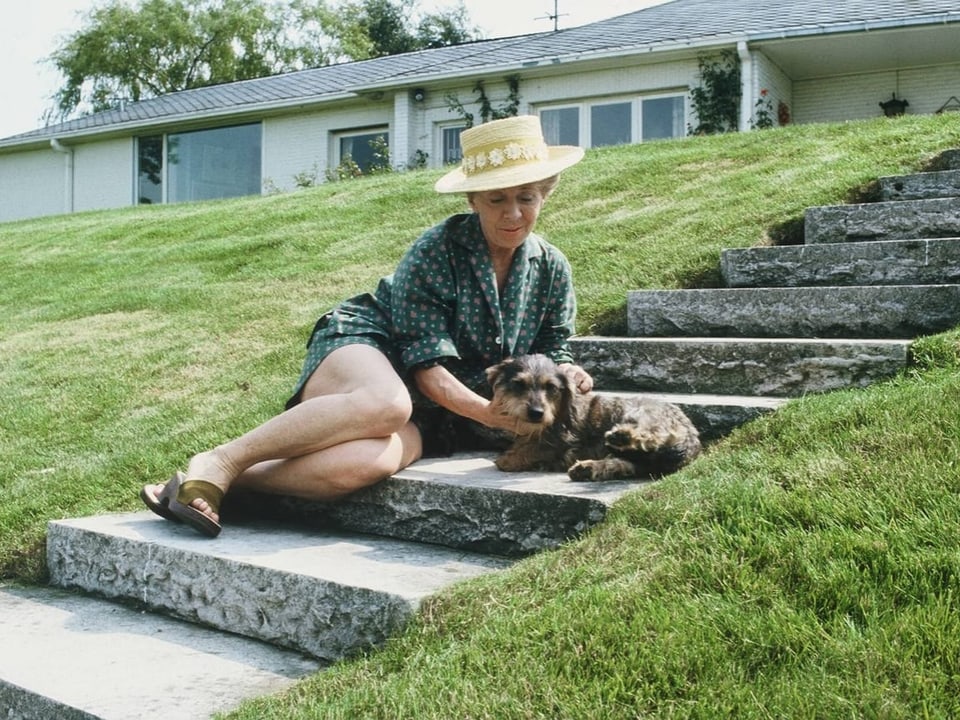 Inge Meisel sitzt auf einer Treppe mit ihrem Dackel.