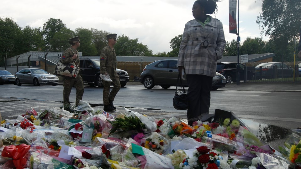 Menschen stehen vor Blumen, wo der britische Soldat ermordet wurde.
