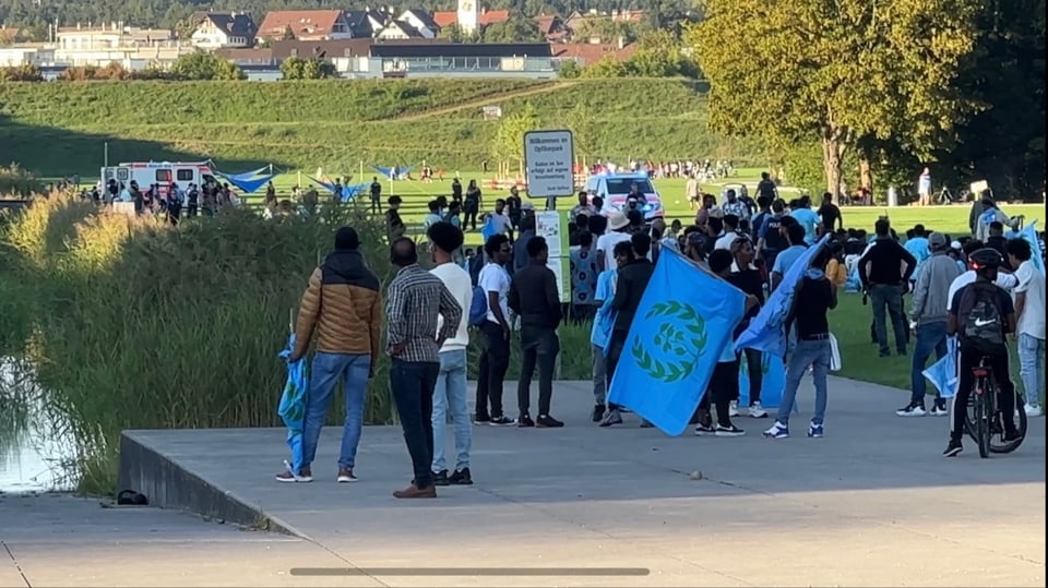 Menschen aus Eritrea treffen sich im Glattpark. Einige haben Flaggen dabei.