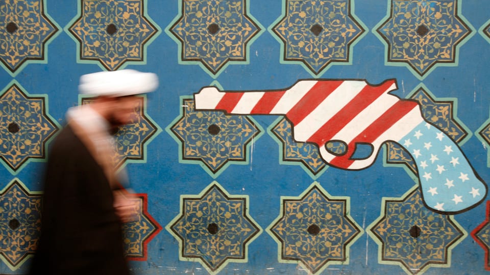 Iranischer Geistlicher läuft an einem Graffiti an der ehemaligen US-Botschaft in Teheran vorbei. 